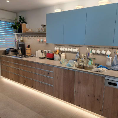 מטבח עם ארונות עץ, כוסות תלויות, מכונת קפה וכלים בכיור