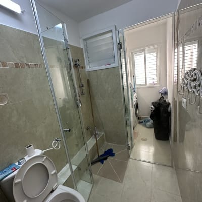 מקלחון זכוכית עם ברזים ומגב על הרצפה