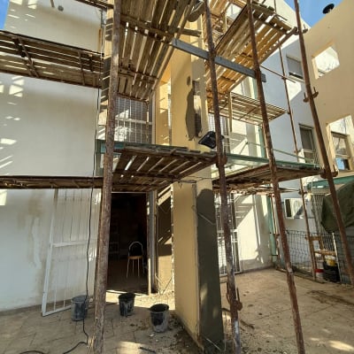 פיגומים, דלי צבע, קיר בשיפוץ, חומרים על הרצפה