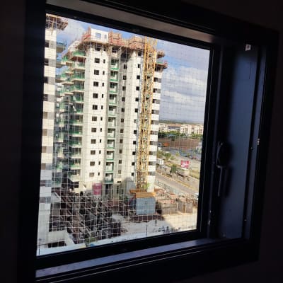 בניין בבנייה עם מנוף ברקע מבעד לחלון