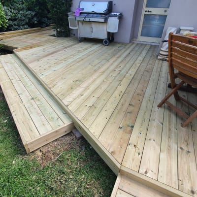 דק עץ בגינה עם גריל וכיסא עץ