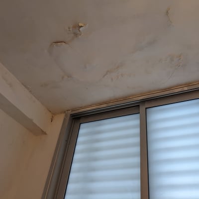 תקרה עם סימני רטיבות ונזק ליד חלון