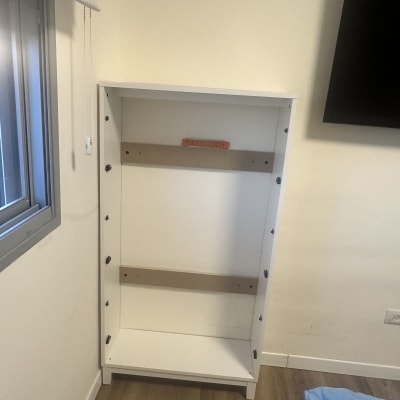 ארון לבן עם מדפים בתהליך הרכבה