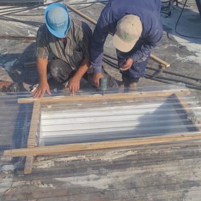 שני אנשים עובדים על איטום גג עם לוחות פלסטיק וכלים