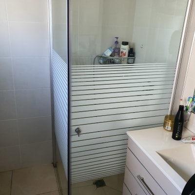 מקלחון זכוכית עם מוצרי טיפוח על מדף