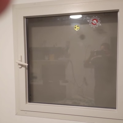 חלון עם ידית לבנה ומדבקות על הזכוכית