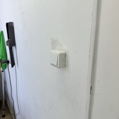 מתג חשמלי על קיר לבן עם כלי עבודה ברקע