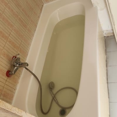 אמבטיה עם מים וברז מקלחת על קיר מרוצף