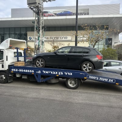 משאית גרר עם רכב שחור על גבי פלטפורמה