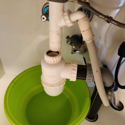 כיור עם צנרת פלסטיק וקערה ירוקה מתחת