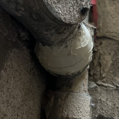 צינור מתכת עם איטום על קיר בטון