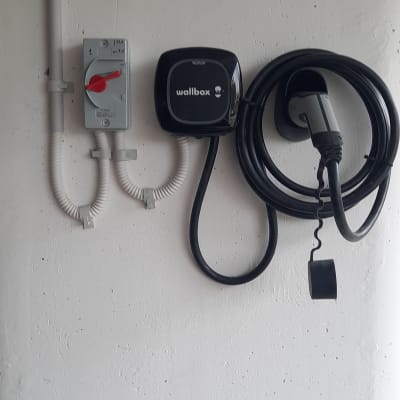 מטען חשמלי לרכב עם כבל תלוי על הקיר