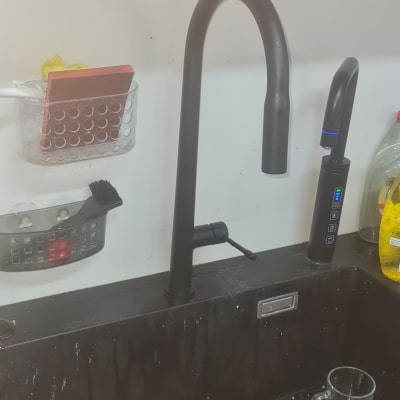 ברז שחור בכיור מטבח עם כלים וסבון