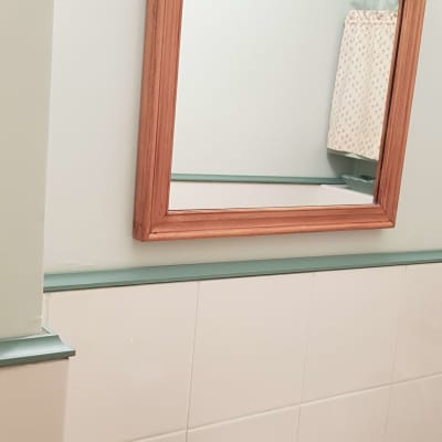 מראה עם מסגרת עץ על קיר חדר אמבטיה