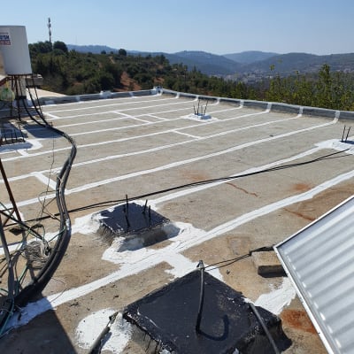 גג עם איטום לבן ושחור, נוף הררי ברקע