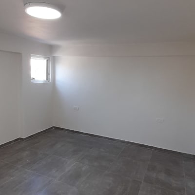 חדר ריק עם קירות צבועים בלבן ורצפת אריחים אפורה