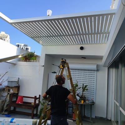 עובד מתקין פרגולה מאלומיניום על גג