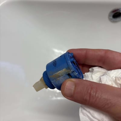 חלק פלסטיק כחול מוחזק ביד ליד כיור