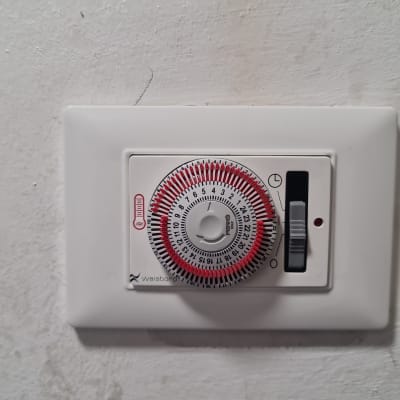 טיימר חשמלי עם חוגה ומתג על קיר