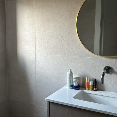 כיור אמבטיה עם מוצרי טיפוח ומראה עגולה