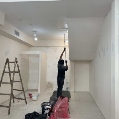 אדם צובע תקרה עם רולר, סולם ודלי צבע