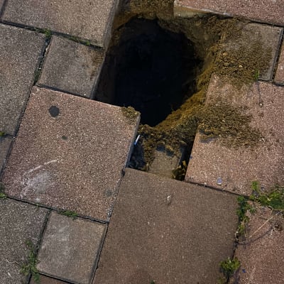 בור פתוח במדרכה עם אדמה חשופה