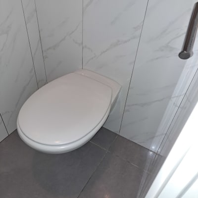 אסלה לבנה על רצפת אריחים אפורה