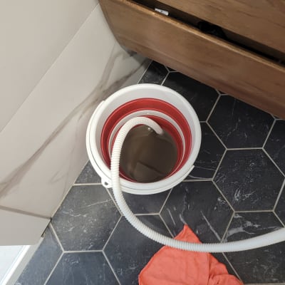 צינור לבן בתוך דלי עם מים על רצפה שחורה