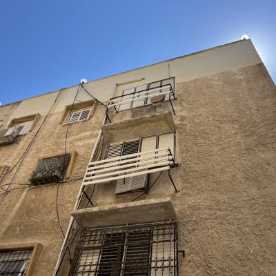 חזית בניין מגורים עם סורגים, תריסים וצנרת בגובה