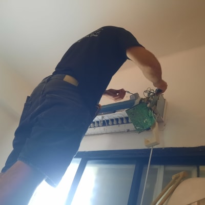 אדם מתקן מזגן על קיר פנימי