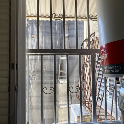 חלון עם סורגי אלומיניום ומסגרת לבנה