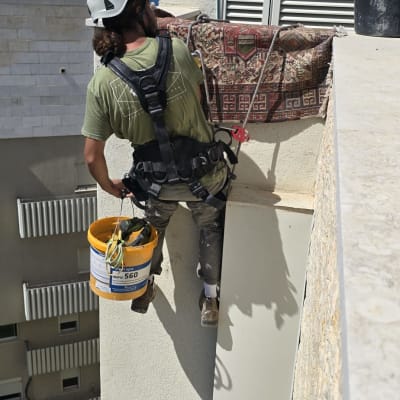 עובד בגובה עם קסדה ורתמה על בניין