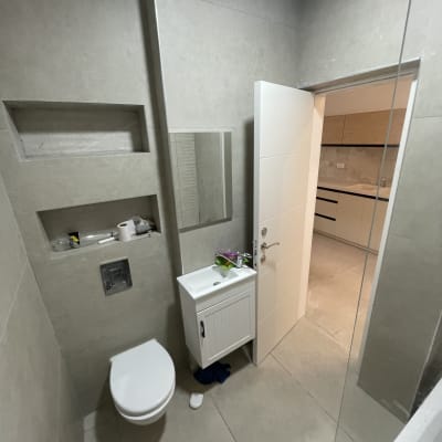 שירותים וחדר אמבטיה עם כיור ודלת פתוחה