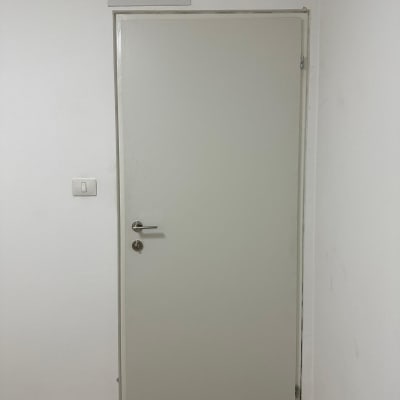 דלת לבנה עם ידית מתכת על רקע קיר לבן