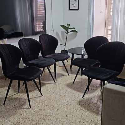 חמש כיסאות שחורים מסודרים בחדר עם שולחן קטן