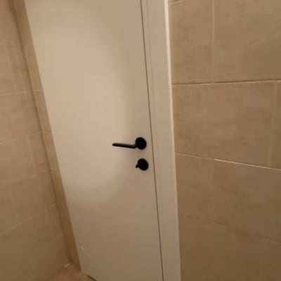 דלת לבנה עם ידית שחורה בחדר אמבטיה