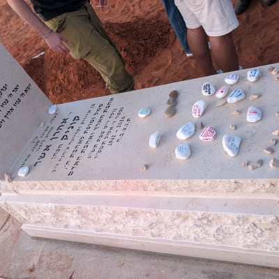 מצבת אבן טבעית בהירה עם כיתוב חרות ואבני זיכרון
