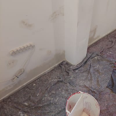 קיר עם תיקוני צבע ודלי צבע על הרצפה