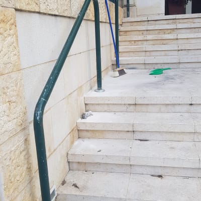 מעקה ירוק לצד מדרגות אבן עם מטאטא ויעה