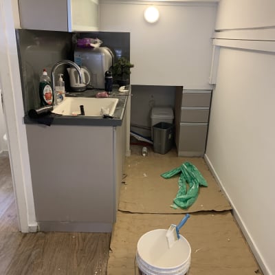 דלי צבע ומברשת על רצפה עם קרטון