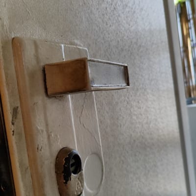 ידית דלת מתכתית על רקע דלת לבנה