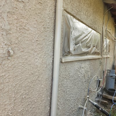 קיר מחוספס עם חלון מכוסה בניילון לקראת צביעה