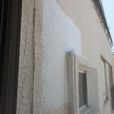 קיר חיצוני עם טיח לבן סביב חלון