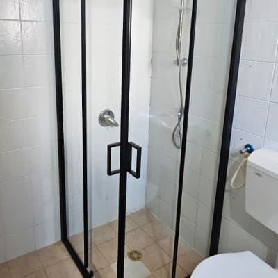 מקלחון זכוכית עם דלתות שחורות וברז מקלחת