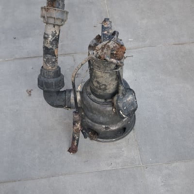 משאבה ישנה עם צינורות חלודים על רצפה אפורה