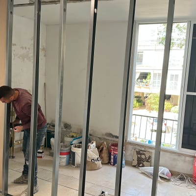 אדם עובד על קיר גבס בחדר במהלך שיפוץ