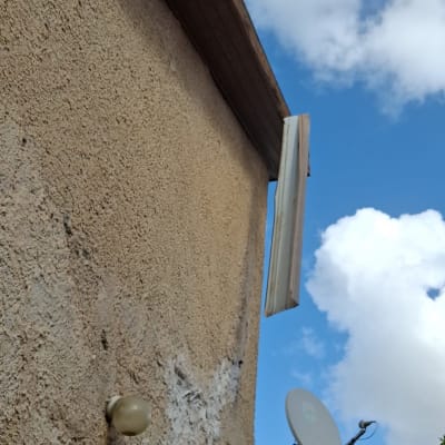 קיר חיצוני עם אנטנה ולוח עץ על הגג