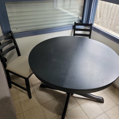 שולחן עגול ושני כיסאות בחדר עם חלונות