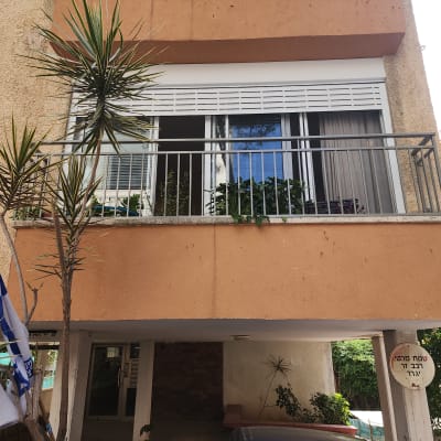 מרפסת עם מעקה מתכת ותריסים לבנים