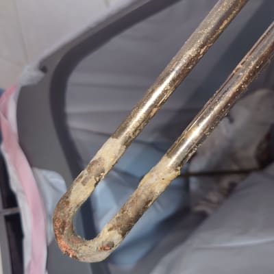 גוף חימום עם אבנית על רקע פח אשפה